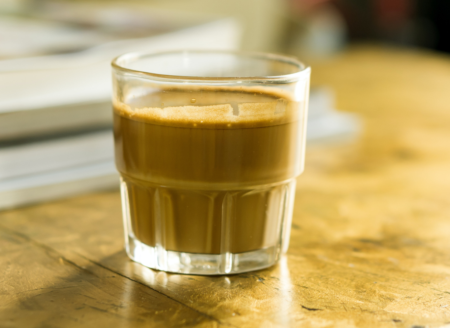 Et glas med kaffe og mælk står på et bord