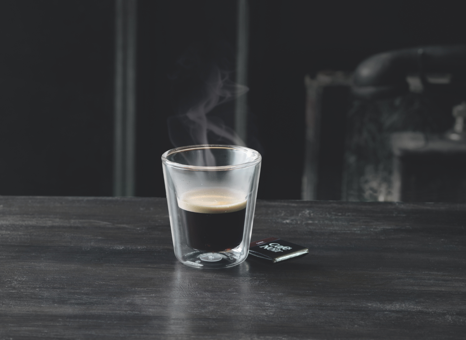 En kop sort espresso står på et sort træbord