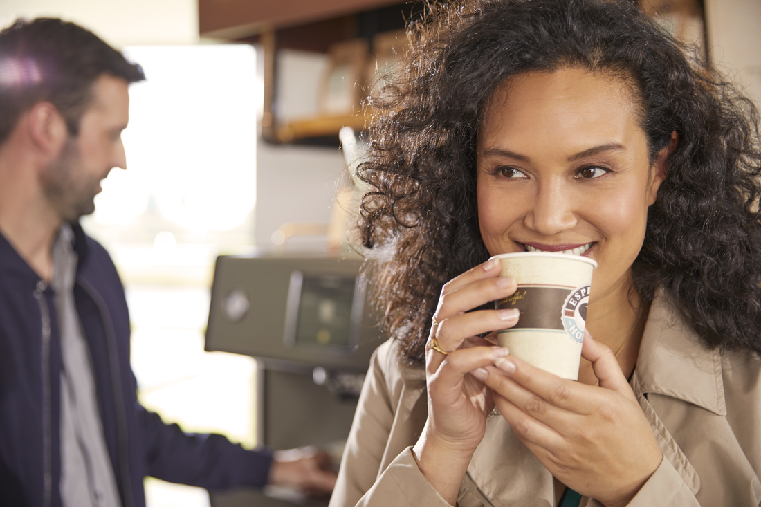 To personer i en kaffebar, én drikker kaffe, den anden står ved kaffemaskinen.