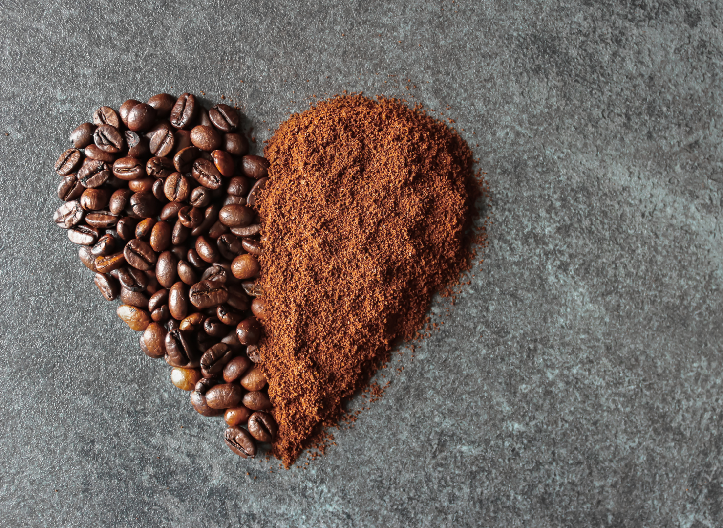 Et hjerte formet med halv kaffebønner og halv kaffepulver