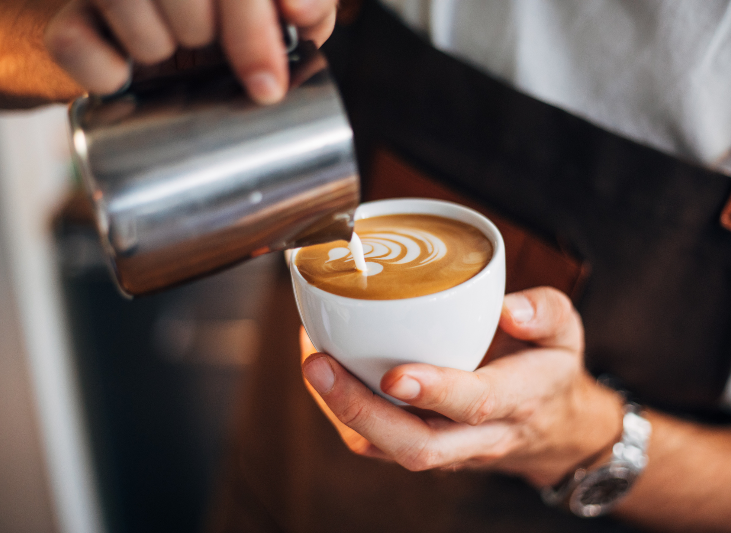Kop kaffe bliver hældt over med mælk