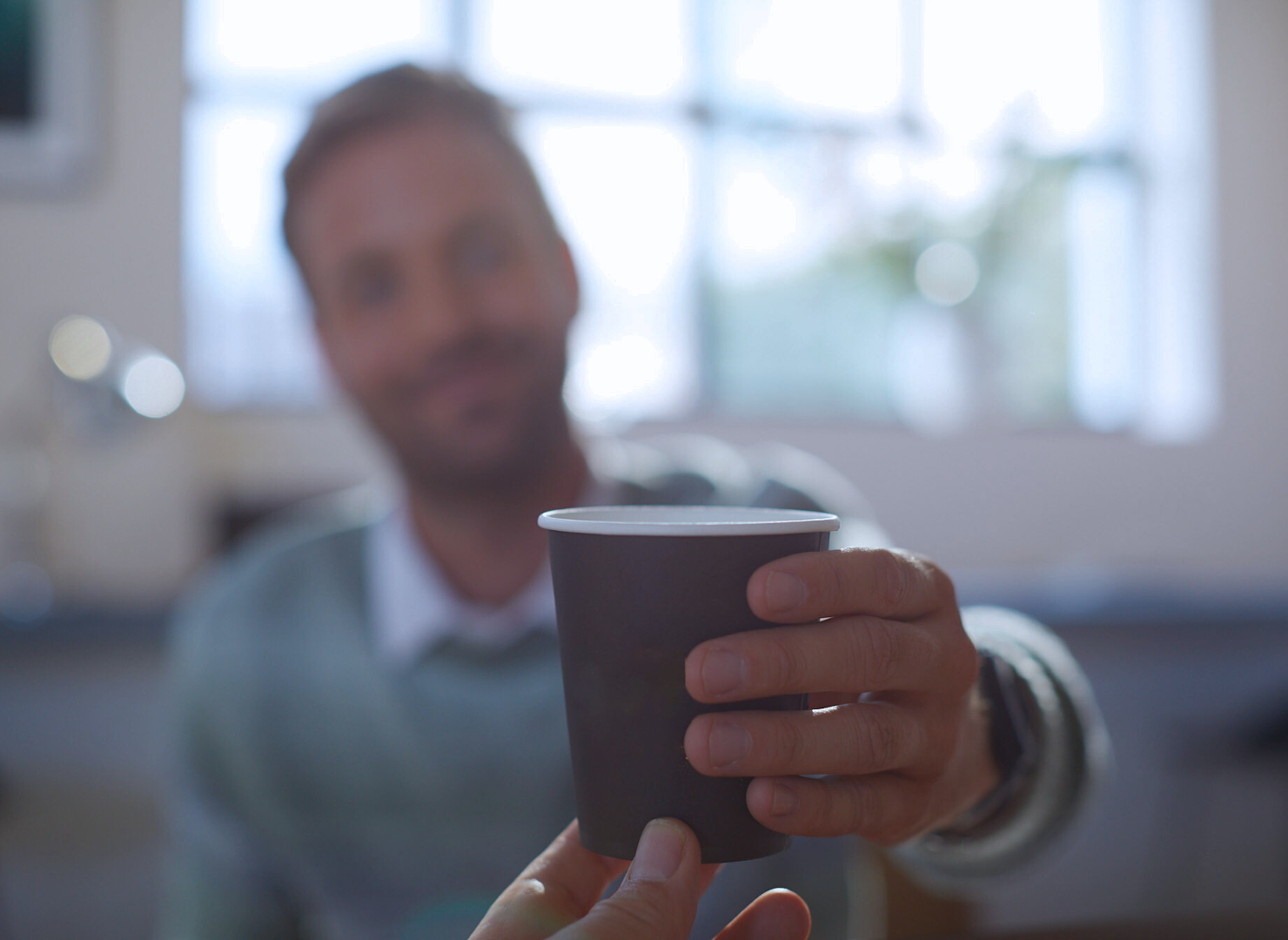 En mand får en kop kaffe i hånden